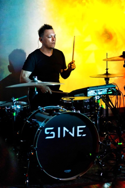 Sonny Sanchez at the drum kit in orange stage light